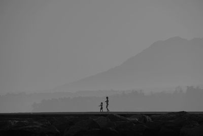 Silhouette man standing on mountain against clear sky