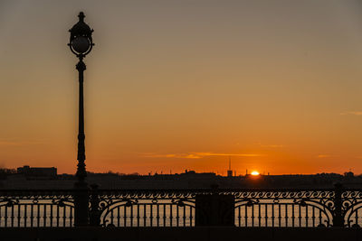 Silhouette street light and bridge against sky during sunset