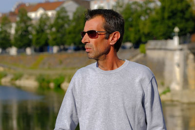 Man wearing sunglasses looking away while standing outdoors