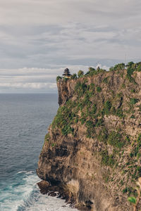 Rock formation by sea against sky