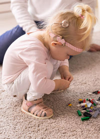 High angle view of girl sitting on sand at home