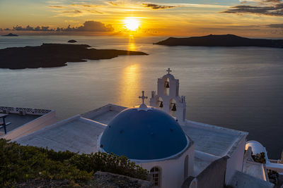 High angle view of sea by buildings against sky during sunset