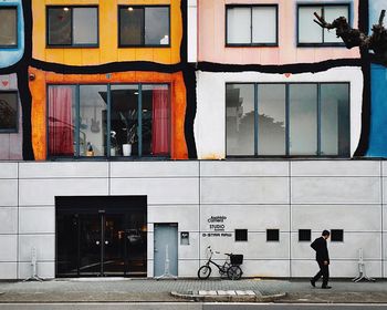 Man walking on sidewalk by building in city