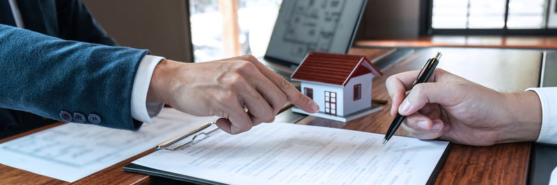 Midsection of man holding paper with text on table