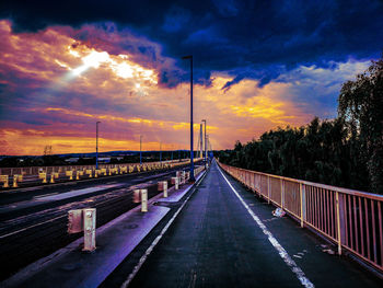 Road by bridge against sky at sunset