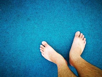 Low section of man standing on blue carpet