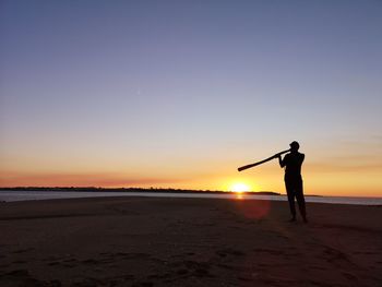 Silhouette man standing at beach against sky during sunset