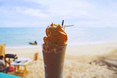 Close-up of drink on beach against sky