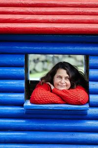 Portrait of woman smiling while leaning on window