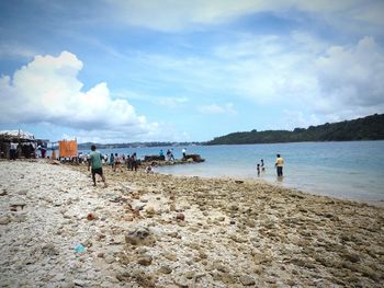 People at beach against sky