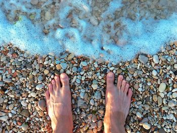 Low section of woman with pebbles in sea