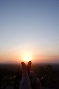 Midsection of person against sun during sunset