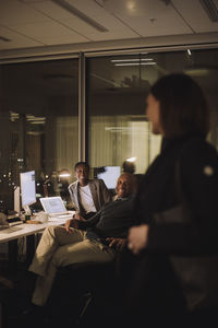 Happy female and male colleagues discussing with businesswoman at work place