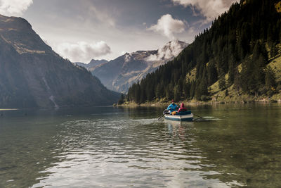 Couple riding in boat at lake vilsalpsee near mountains, tyrol, austria