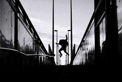 Rear view of silhouette man jumping against sky