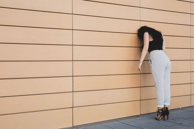 Woman leaning against brown wall