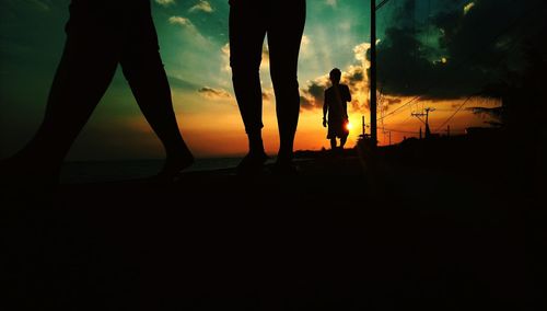 Low section of silhouette people walking against sky during sunset