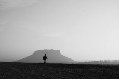 Man walking on field against clear sky