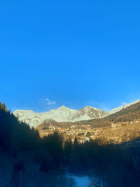 Scenic view of snowcapped mountains against clear blue sky