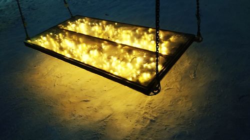 High angle view of illuminated light on table against wall