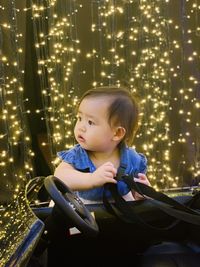 Portrait of boy sitting on illuminated christmas tree