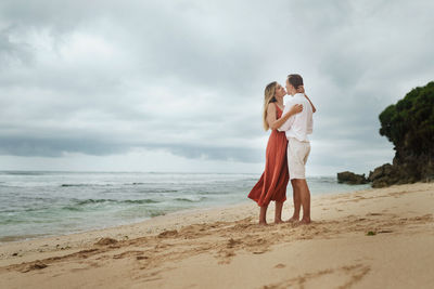 Couple standing on beach against sea