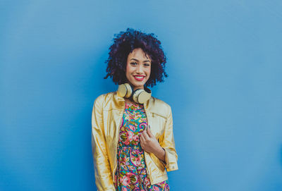 Fashionable young woman with curly hair against blue background