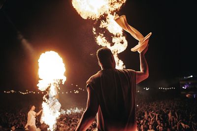 Rear view of man with arms outstretched at night