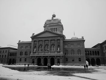 People in front of building against clear sky