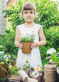 Portrait of young woman holding potted plant