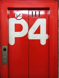 Close-up of number with no smoking sign on red door