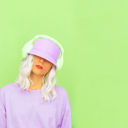 Beautiful woman wearing hat against green background