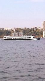 Boat sailing in river in front of city against sky