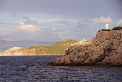 Scenic view of sea by mountain against sky