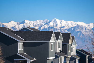 Houses against snowcapped mountains against clear blue sky