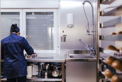 Rear view of female chef making food in commercial kitchen