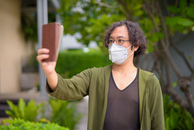 Portrait of man holding camera while standing outdoors