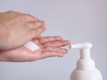 Close-up of woman holding hands over white background