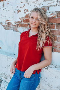 Portrait of a smiling young woman against wall