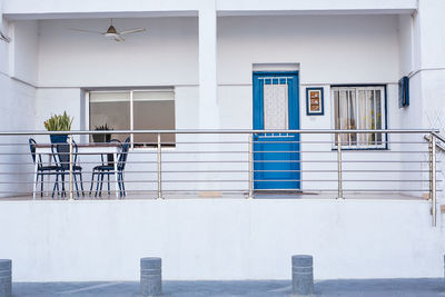 Empty chairs and table against building