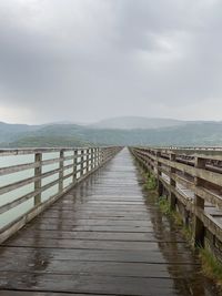 Wooden pier leading towards sea against sky