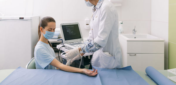 Midsection of doctor examining patient in clinic