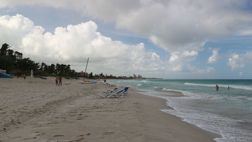 Panoramic view of people on beach against sky
