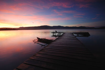 Pier over lake against sky during sunset