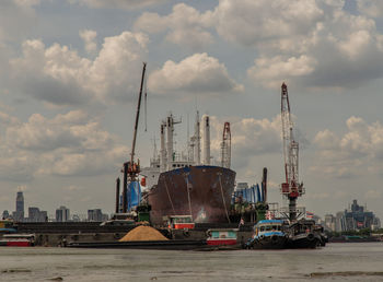 Cranes at commercial dock against sky