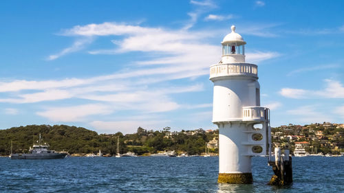 Lighthouse by sea against sky