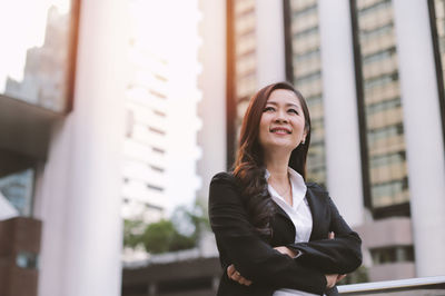 Smiling businesswoman standing against modern building