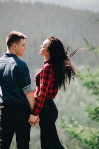 Side view of young couple standing face to face in forest