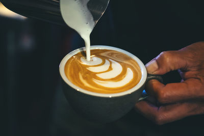 Cropped image of hand pouring coffee in cup