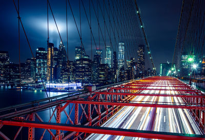 Illuminated bridge and buildings against sky at night